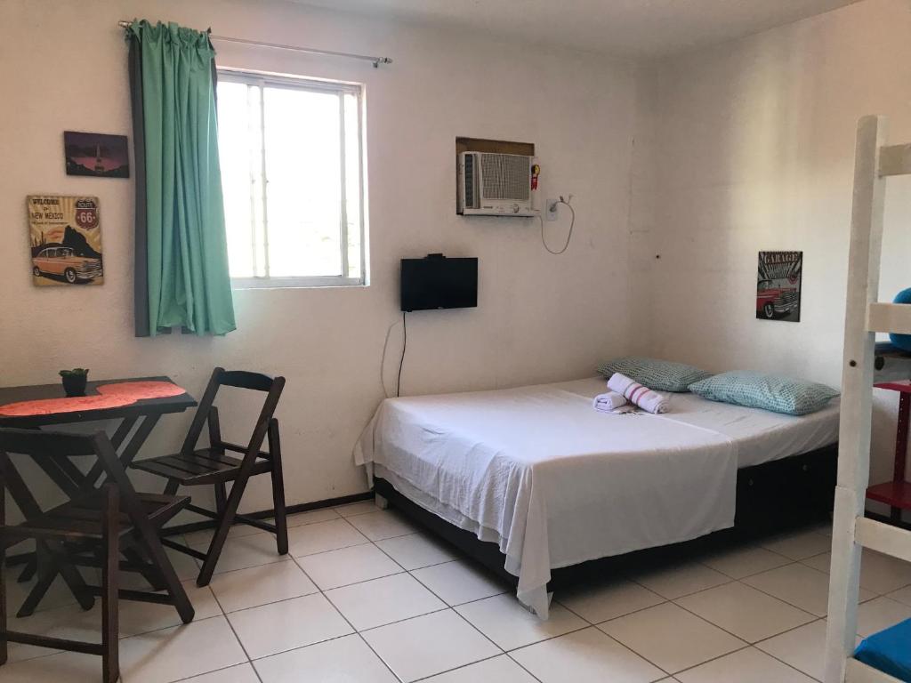 a bedroom with a bed and a table and a window at Studio Piedade in Recife