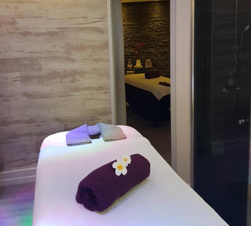a white bed with purple towels and flowers on it at Le Trophée Boutique Hôtel Spa- La Loggia Appart'hôtel in Deauville