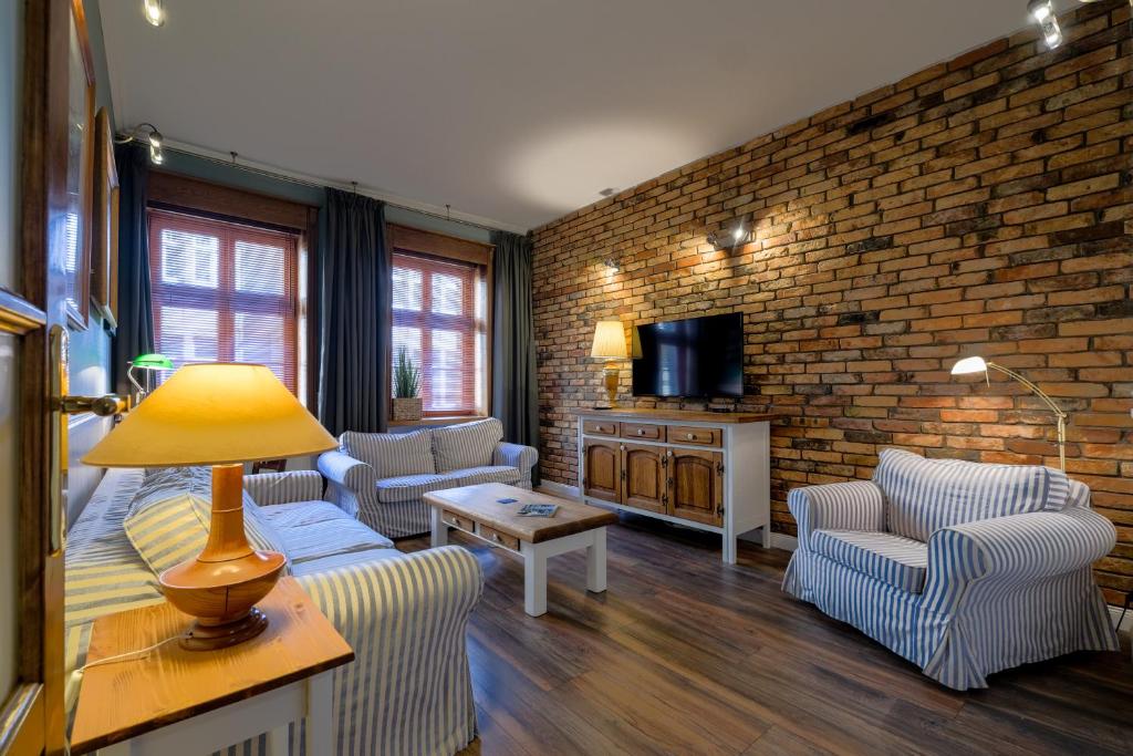 - un salon avec des canapés et un mur en briques dans l'établissement Old House Apartments Poznań, à Poznań