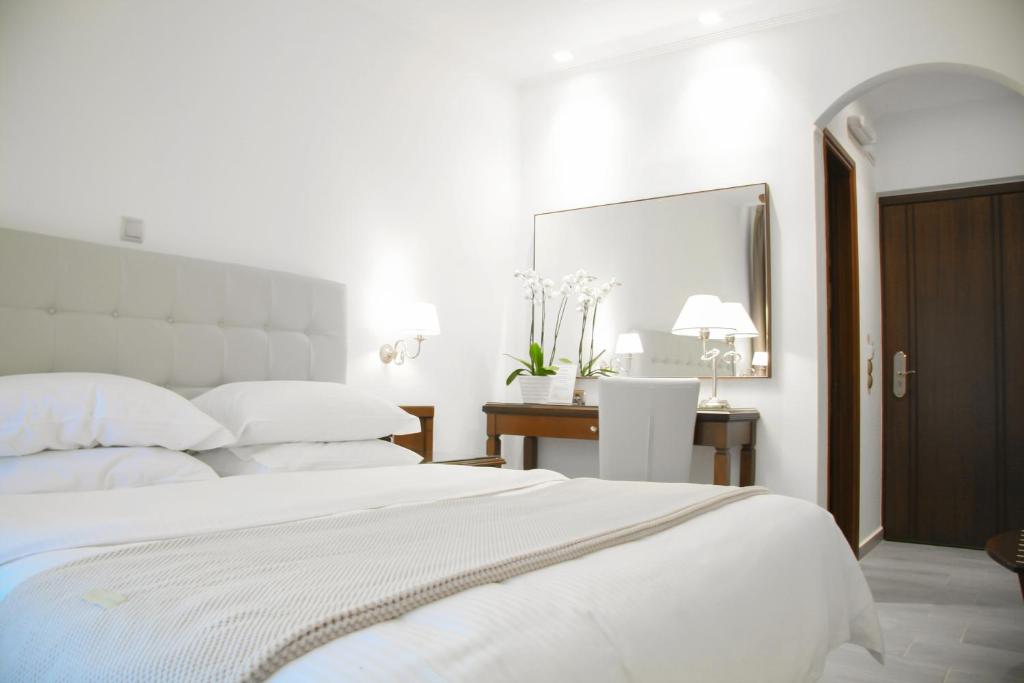 a white bedroom with a large bed and a desk at Armata Boutique Hotel in Spetses