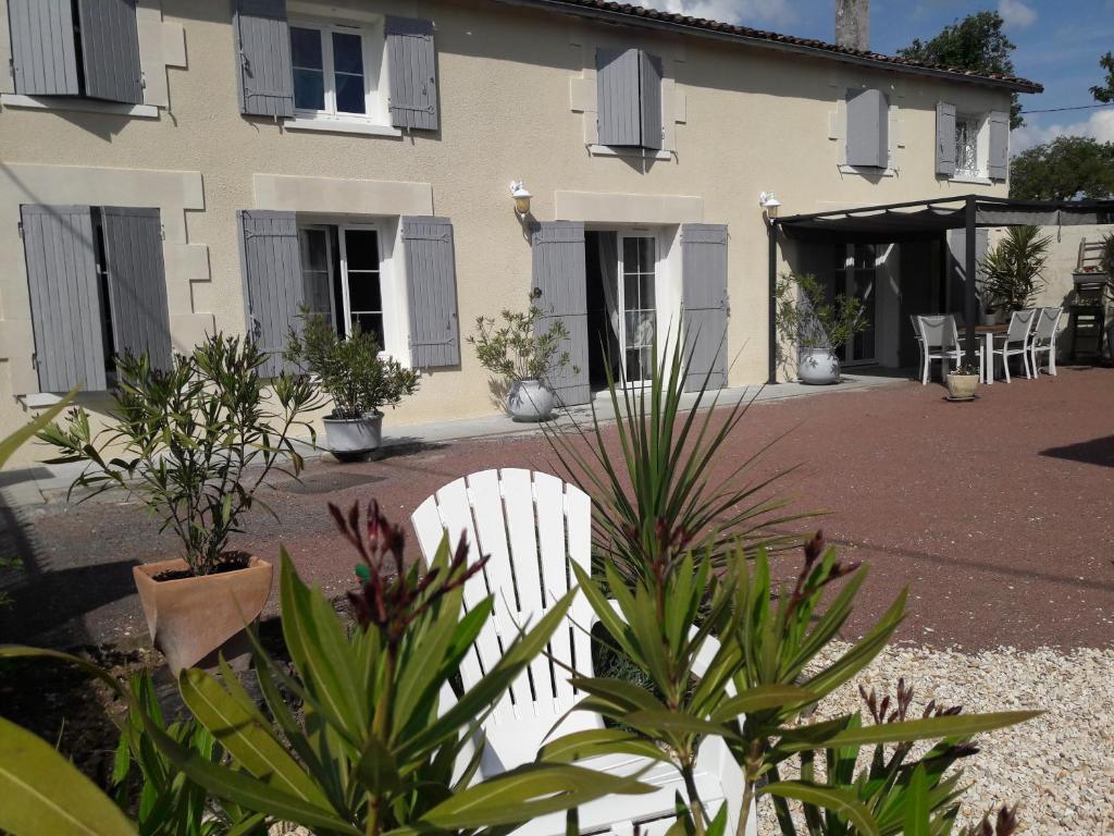 uma cadeira branca em frente a uma casa com plantas em La charentaise ch d'hôtes ,Studio em Chérac