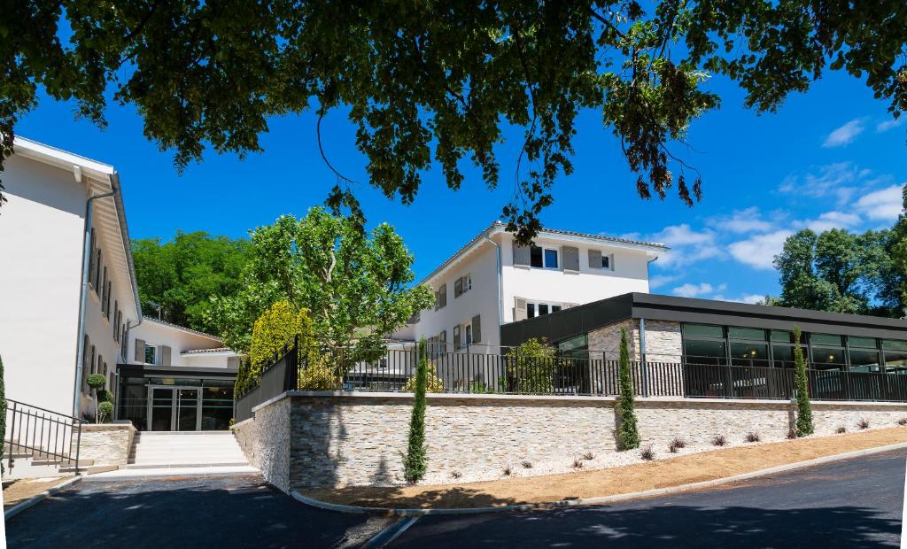 un edificio blanco con una valla y árboles en Le Cottage de Clairefontaine en Chonas-lʼAmballan