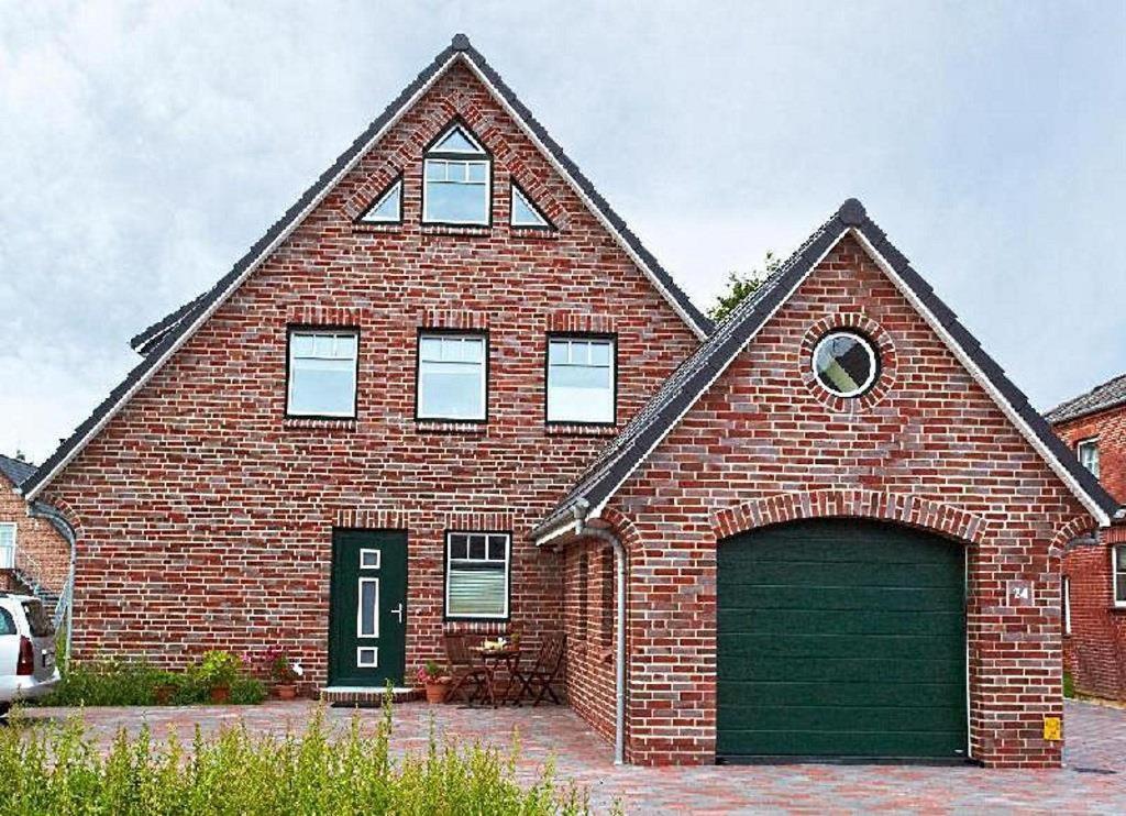 a large brick house with a green garage at Ferienwohnungen Meeresgruss in Sankt Peter-Ording