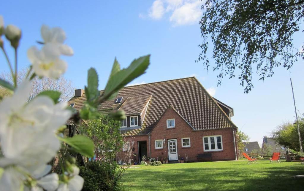 czerwony dom z zielonym ogródkiem przed nim w obiekcie Landhaus op de Warft w mieście Vollerwiek