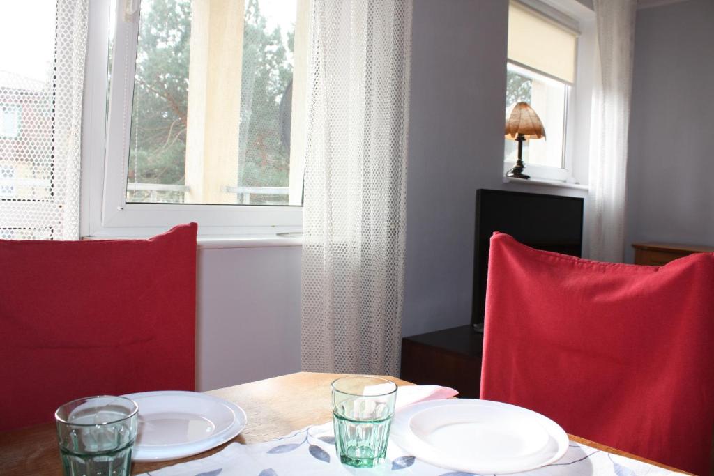 mesa de comedor con 2 sillas rojas y ventana en Apartament Sosnowy en Ustka
