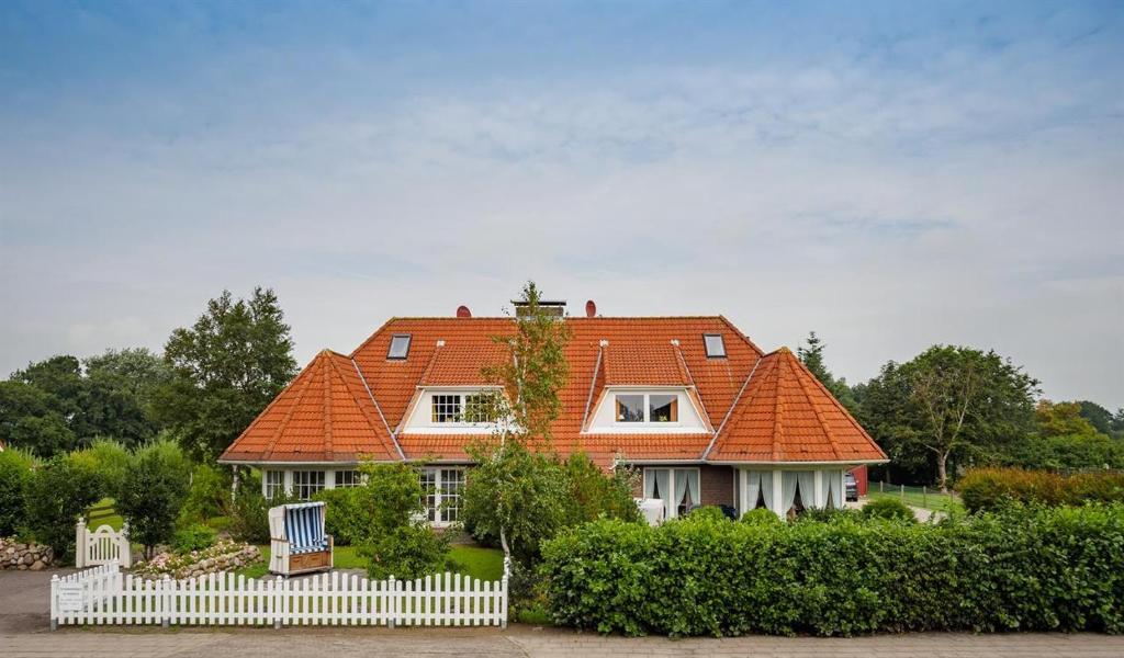 une maison avec un toit orange et une clôture blanche dans l'établissement Haus Georgi, à Sankt Peter-Ording