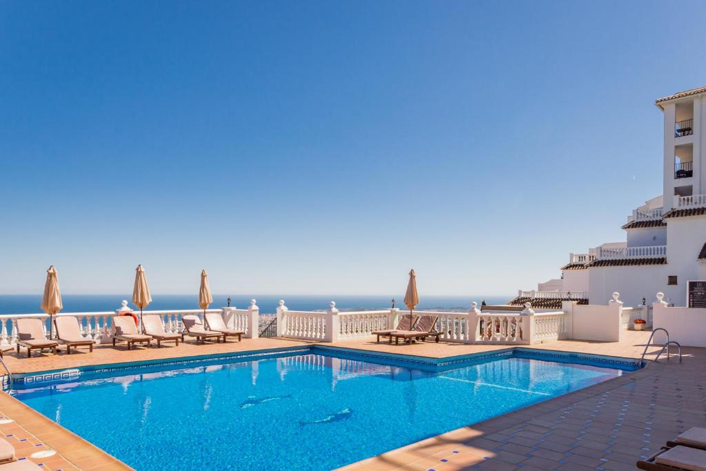 a swimming pool with chairs and the ocean in the background at Macdonald La Ermita Resort in Mijas