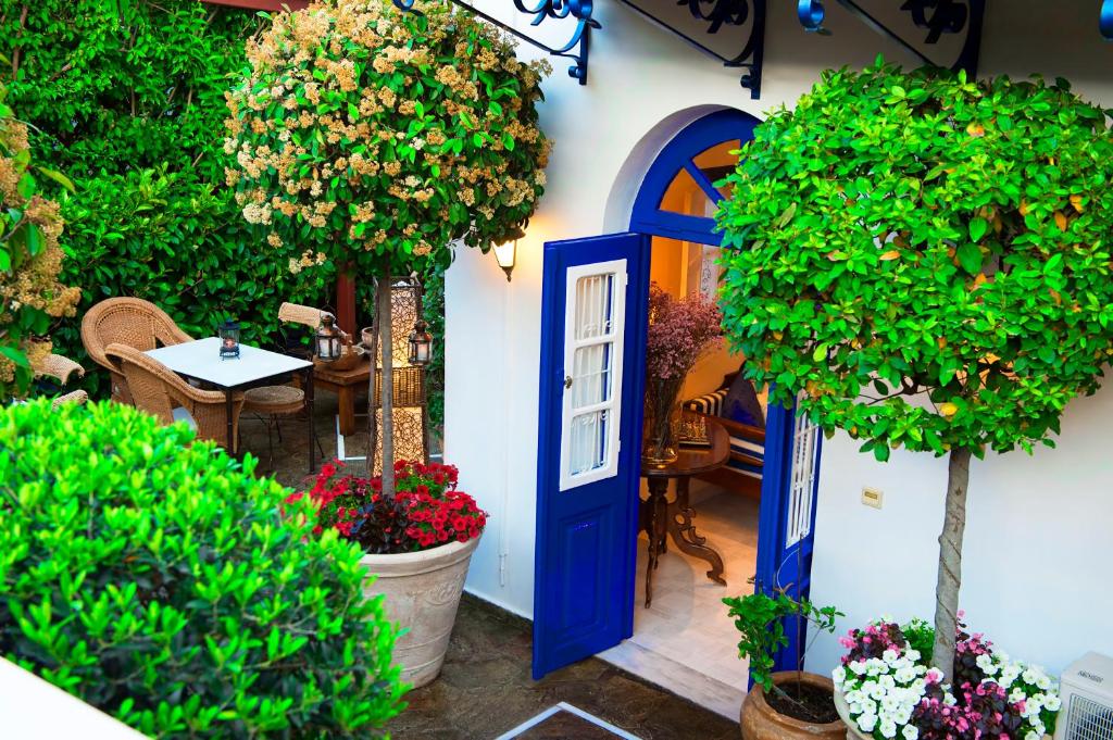 a house with a blue door and trees and flowers at Armata Boutique Hotel in Spetses