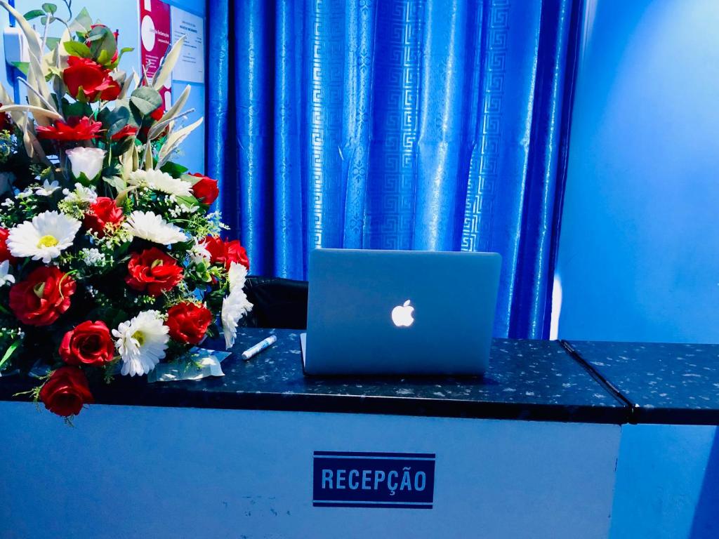 a laptop computer sitting on a counter with flowers at Lisbon Prime Hostel & Rooms in Lisbon