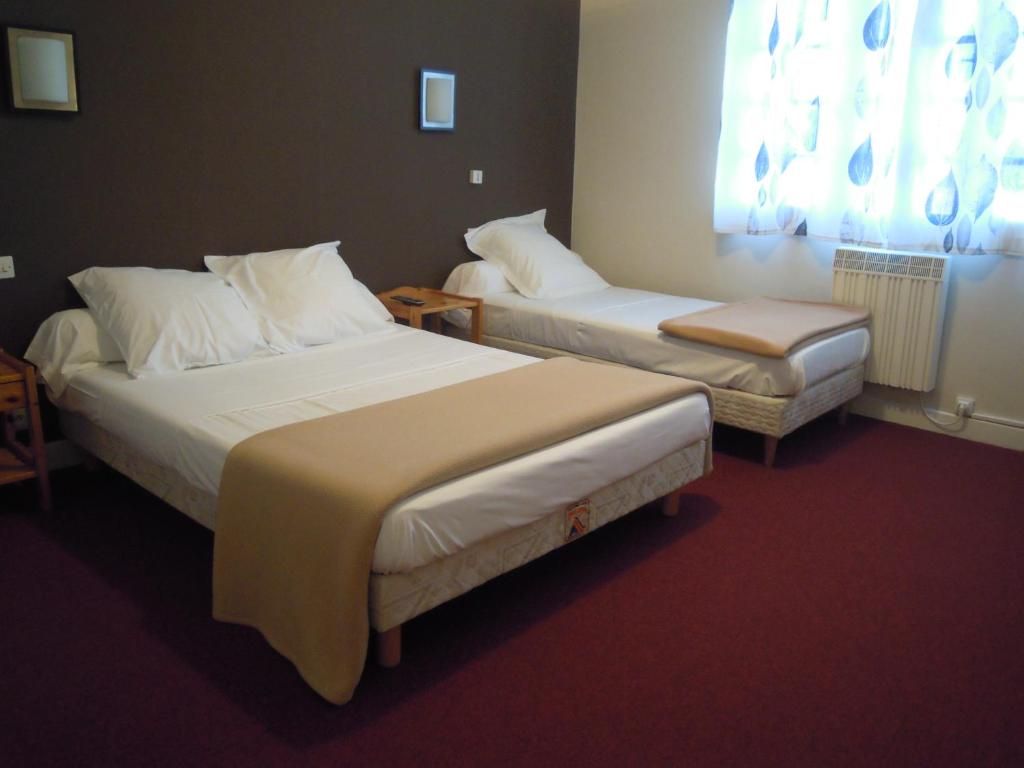 a hotel room with two beds and a table at Hôtel Cuulong in Labarthe-Inard