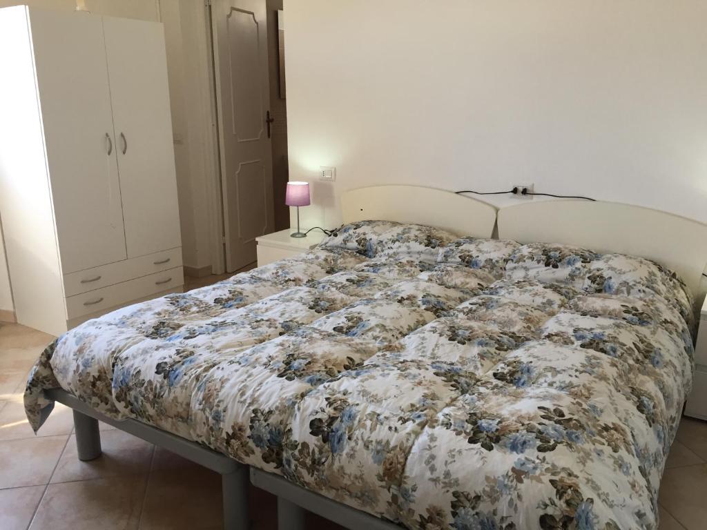 een slaapkamer met een bed met een bloemdekbed bij Ginepro family in Valledoria