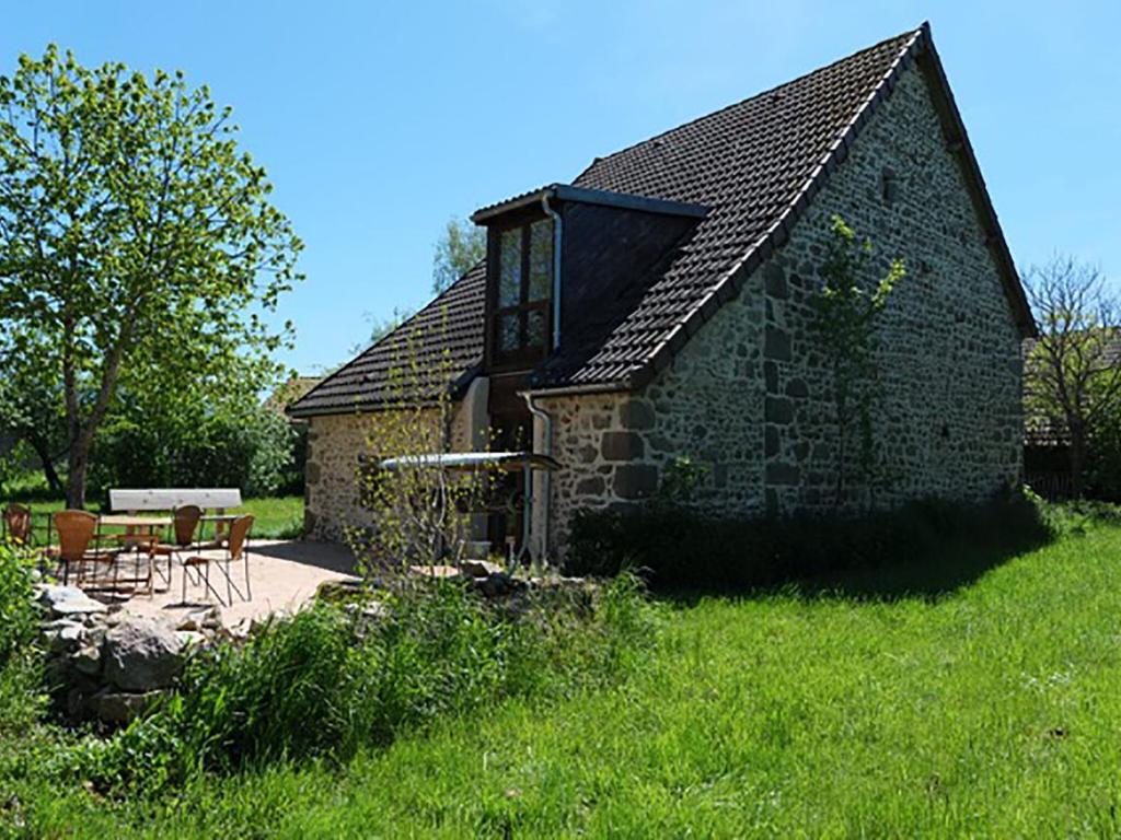 un edificio de piedra con una mesa y sillas delante de él en Charming holiday home overlooking the valley, en Lapeyrouse