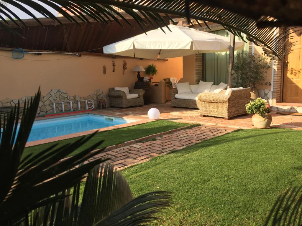 Casa Gle في SantʼAndrea: حديقه خلفيه فيها مسبح ومظله