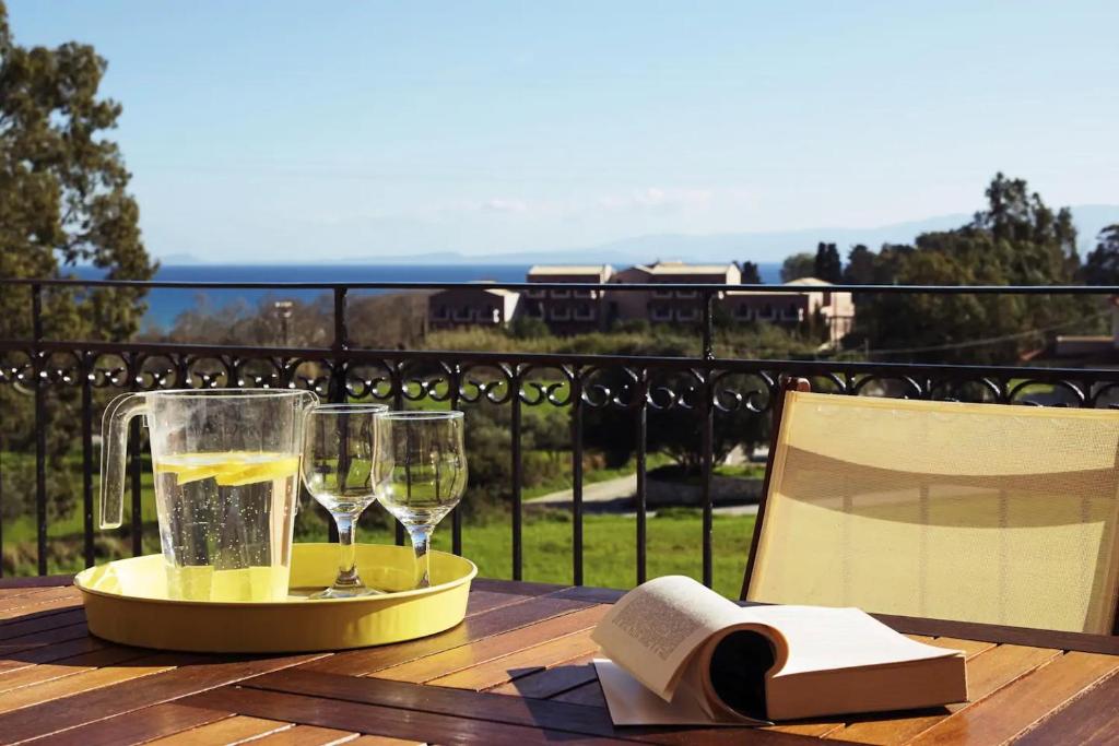 a table with wine glasses and a book on a balcony at Sunny Coco mat villa in Katelios with a sea view in Katelios