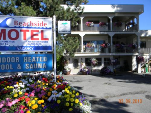 a motel sign in front of a building with flowers at Beachside Motel in Penticton