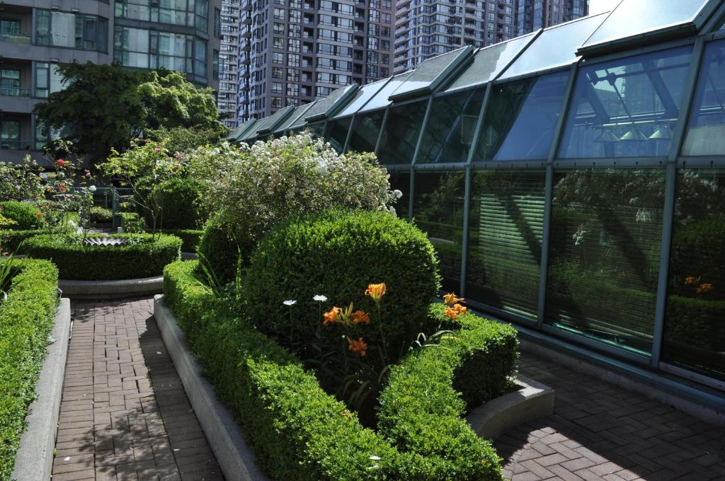 a garden in front of a glass building at Rosedale on Robson Suite Hotel in Vancouver