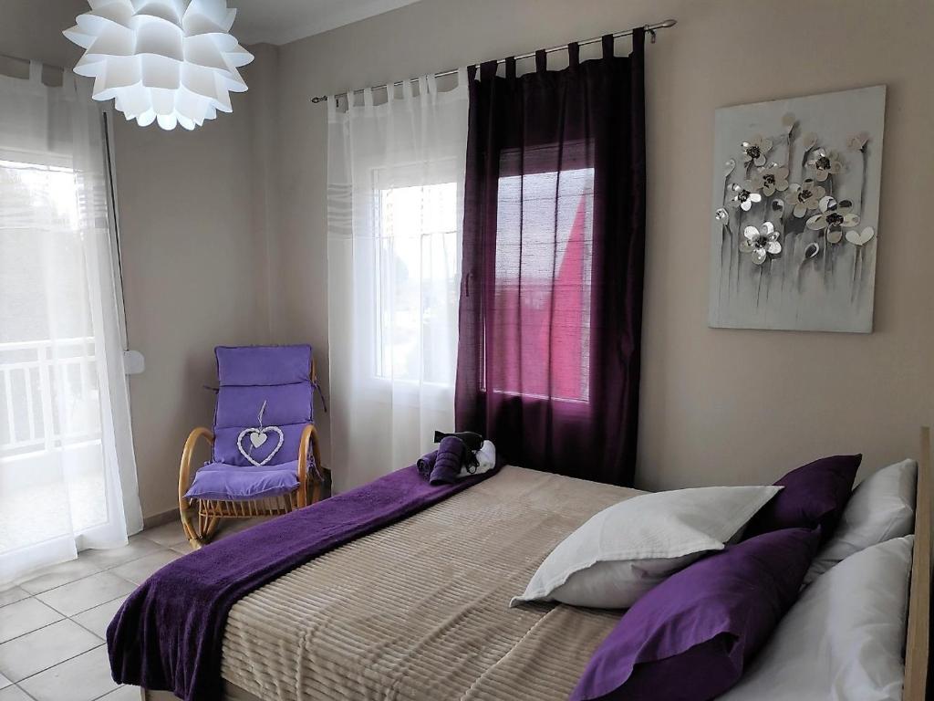 Un dormitorio con una cama con sábanas moradas y una silla en Cozy apartments, en Komotiní