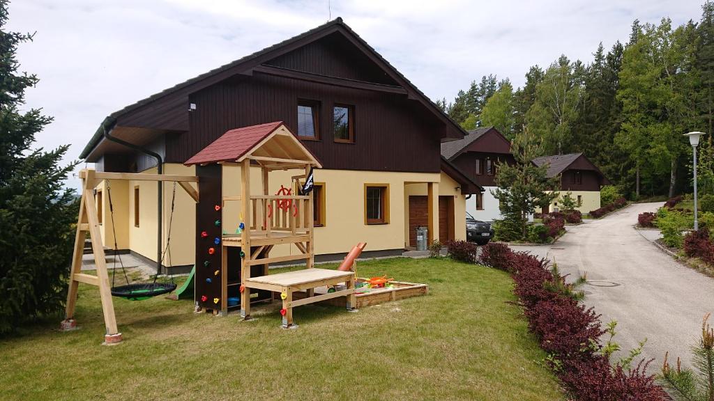 une petite maison avec une aire de jeux dans la cour dans l'établissement Villa Park Lipno 206, à Lipno nad Vltavou