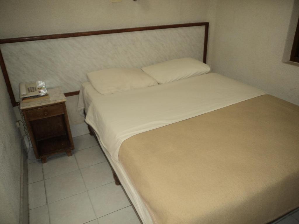 a small bedroom with a bed and a night stand at Hotel Kuraica in Ciudad Obregón