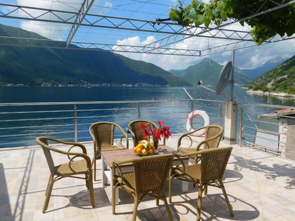 een tafel en stoelen op een balkon met uitzicht op een meer bij Apartman Posejdon in Kotor