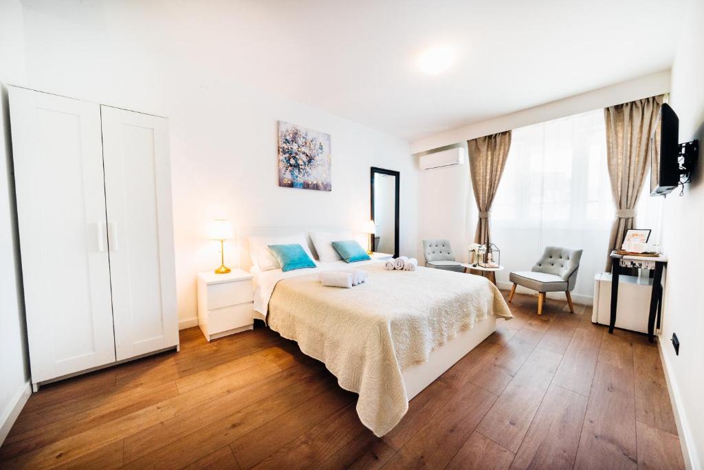 a white bedroom with a bed and a desk at The Harmony Rooms in Split