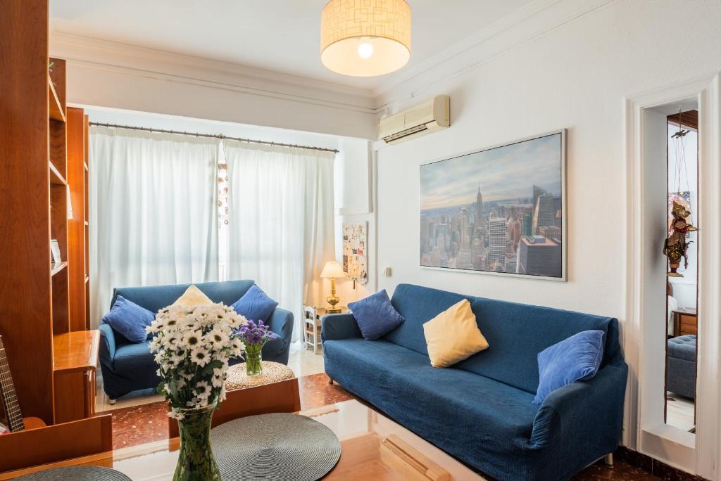 ein Wohnzimmer mit einem blauen Sofa und einem Fenster in der Unterkunft Apartamento Triana Los Remedios in Sevilla