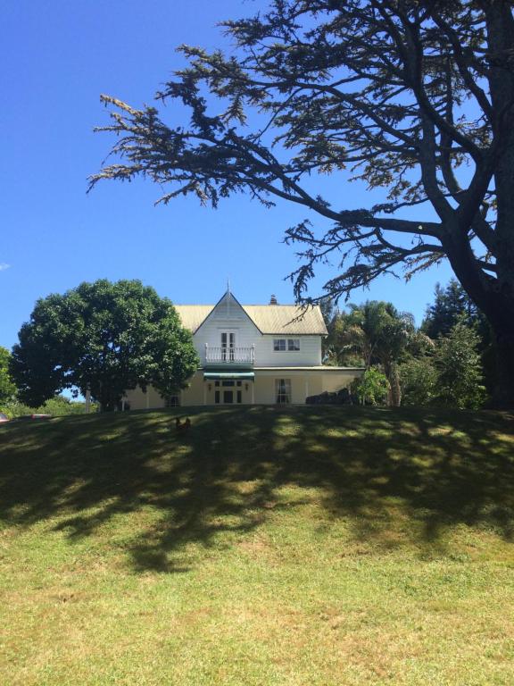 a large white house on a hill with a tree at Paheke Boutique Lodge in Kaikohe