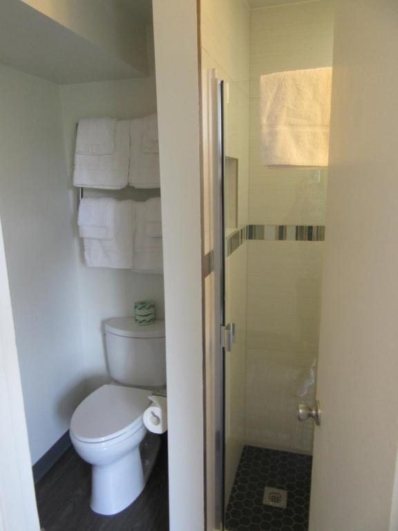 a bathroom with a toilet and a shower with towels at Waikiki Central Hotel - No Resort Fees in Honolulu
