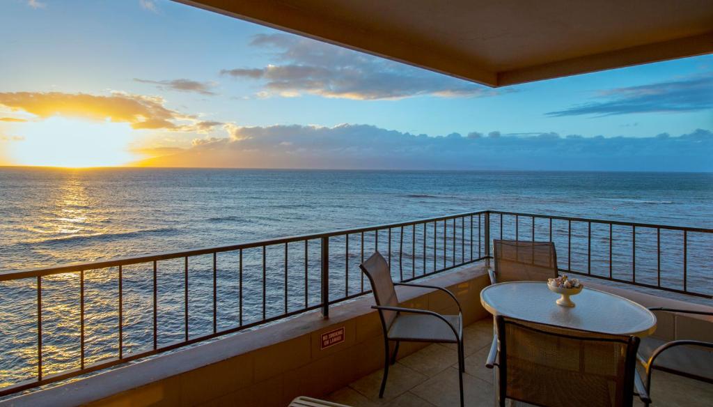uma varanda com uma mesa e cadeiras e o oceano em Maui Kai Condos em Lahaina