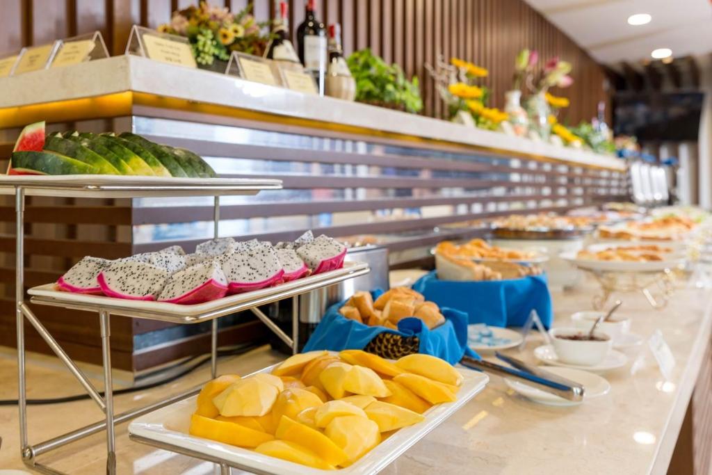 A long breakfast buffet with fruit, pastries, and prepared dishes.