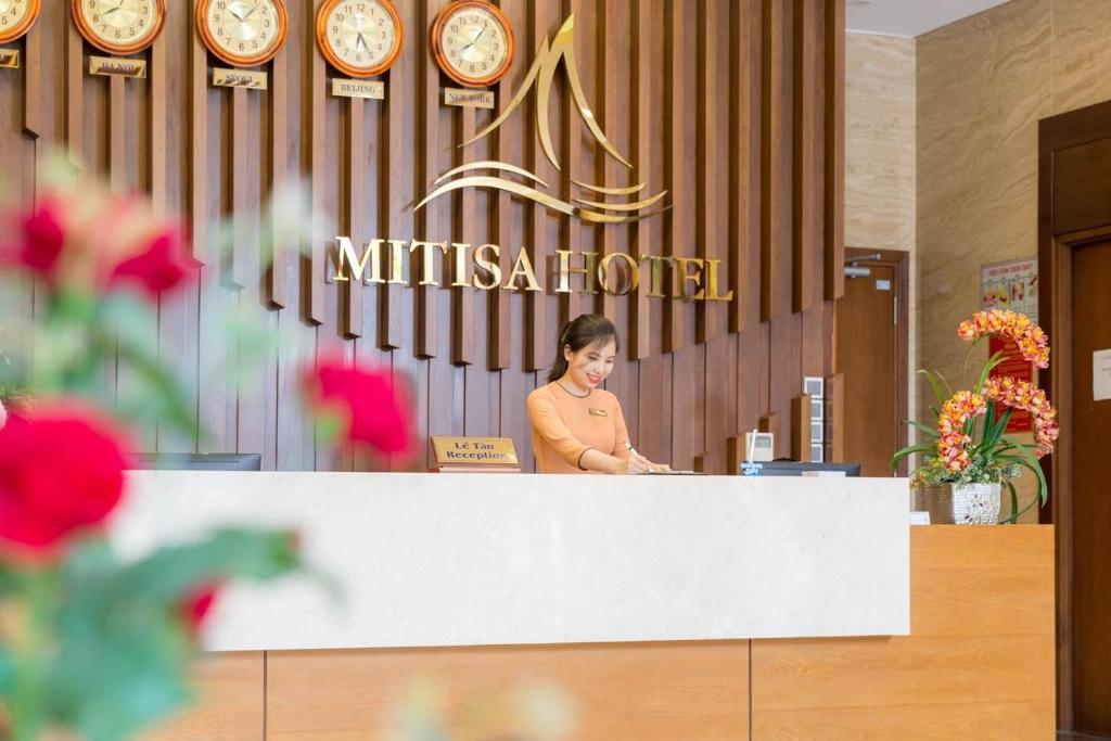 A staffed reception desk sits beneath the hotel’s wall of clocks.