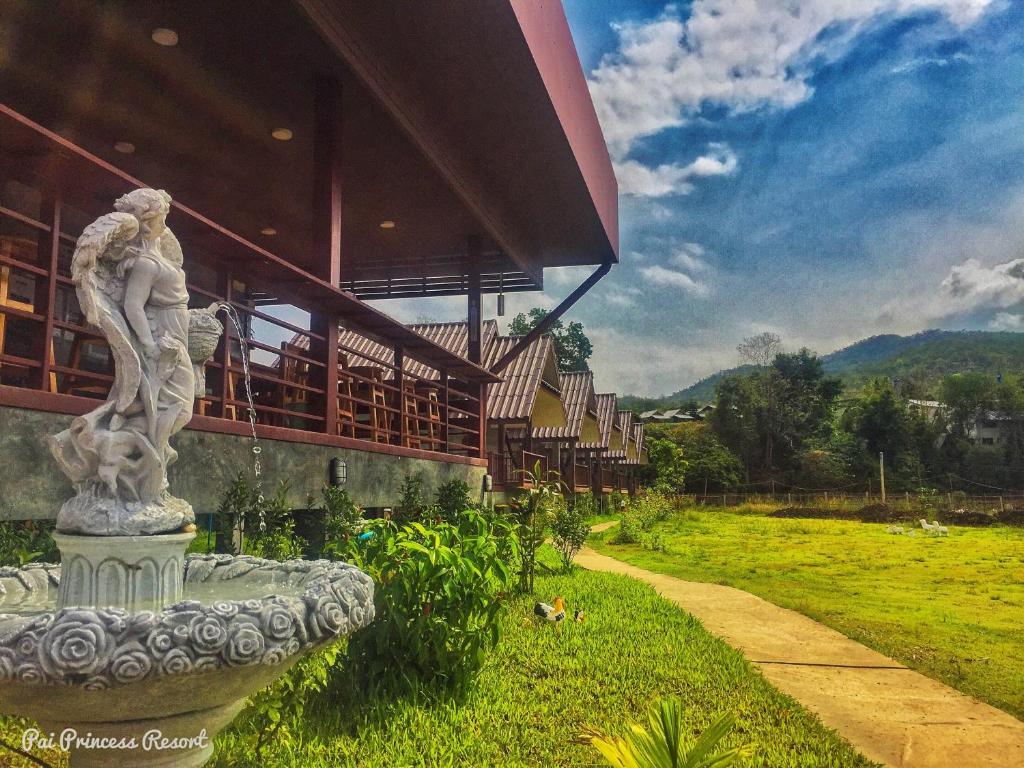 Une statue assise dans l'herbe devant un bâtiment dans l'établissement Pai Princess Resort, à Pai