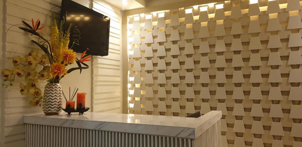 una habitación con TV y un jarrón con flores en un mostrador en RNR Suites, en Legazpi