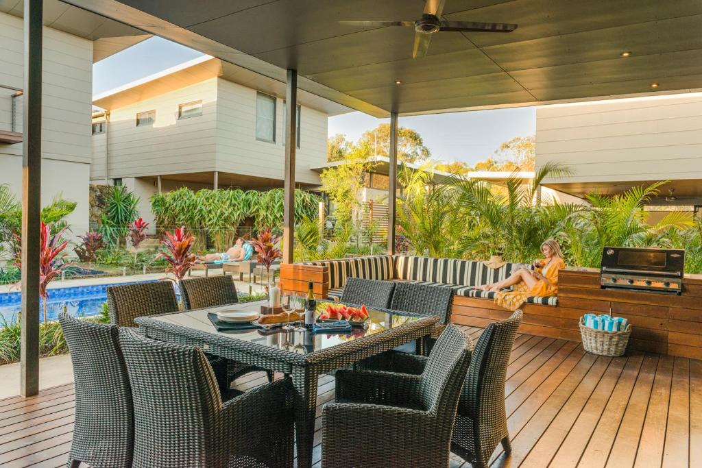 a patio with a table and chairs and a pool at Byron Luxury Beach Houses in Byron Bay