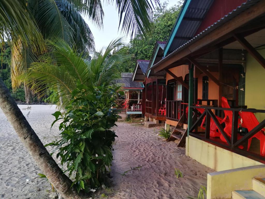 een resort met een palmboom naast een gebouw bij Rainbow Tioman Cottage in Kampong Juara