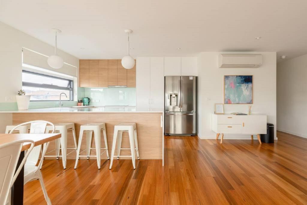 Kangaroo Bay Apartments في هوبارت: مطبخ مع أرضيات خشبية وطاولة مطبخ مع كراسي