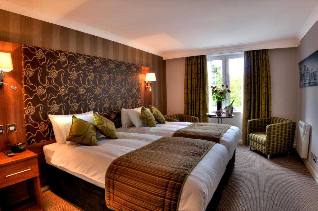 a hotel room with two beds and a large headboard at The Collection Hotel Birmingham in Birmingham