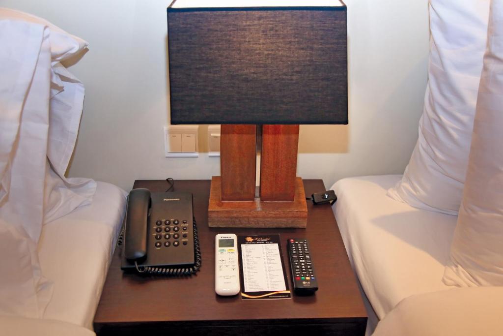 a desk with a lamp and a phone on a table between two beds at PROXY by The Oriental Albay in Legazpi