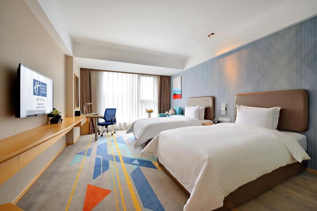 Holiday Inn Express Chengdu Tianhe, an IHG Hotel في Pi: غرفه فندقيه سريرين وتلفزيون