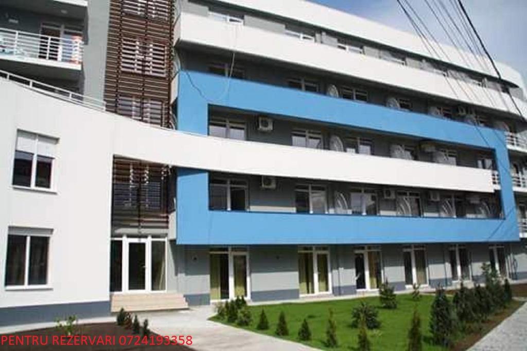 - un bâtiment bleu et blanc avec une cour verdoyante dans l'établissement Garsoniera Soarelui, à Eforie Nord