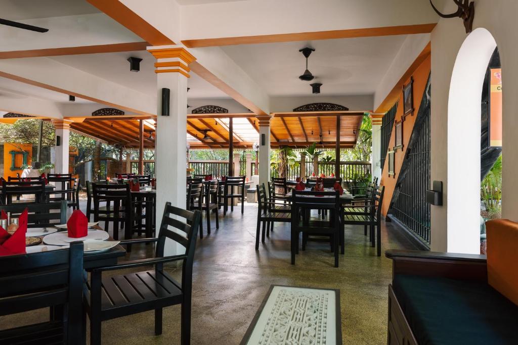 a restaurant with wooden tables and chairs and a patio at Amal Beach Hotel in Bentota