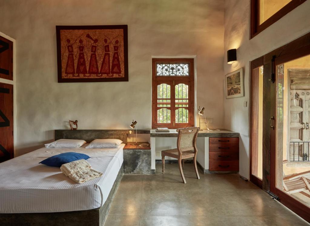 a bedroom with two beds and a desk and a window at Bamboo Villa Kandy in Digana