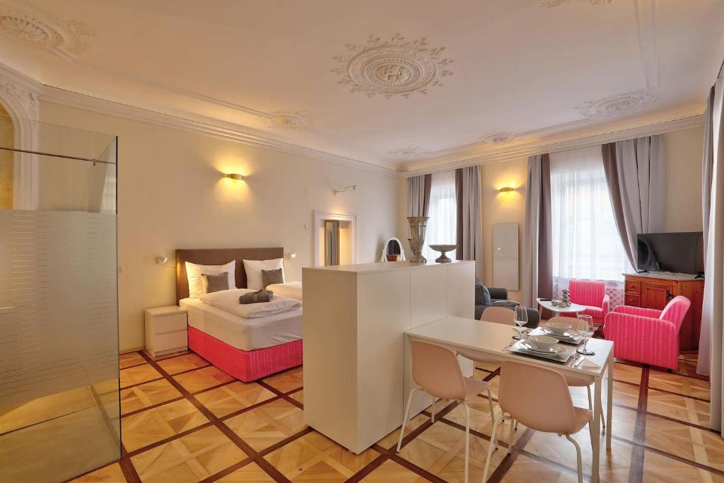 クラーゲンフルトにあるStylische Cityapartments Benediktのベッド、テーブル、椅子が備わるホテルルームです。