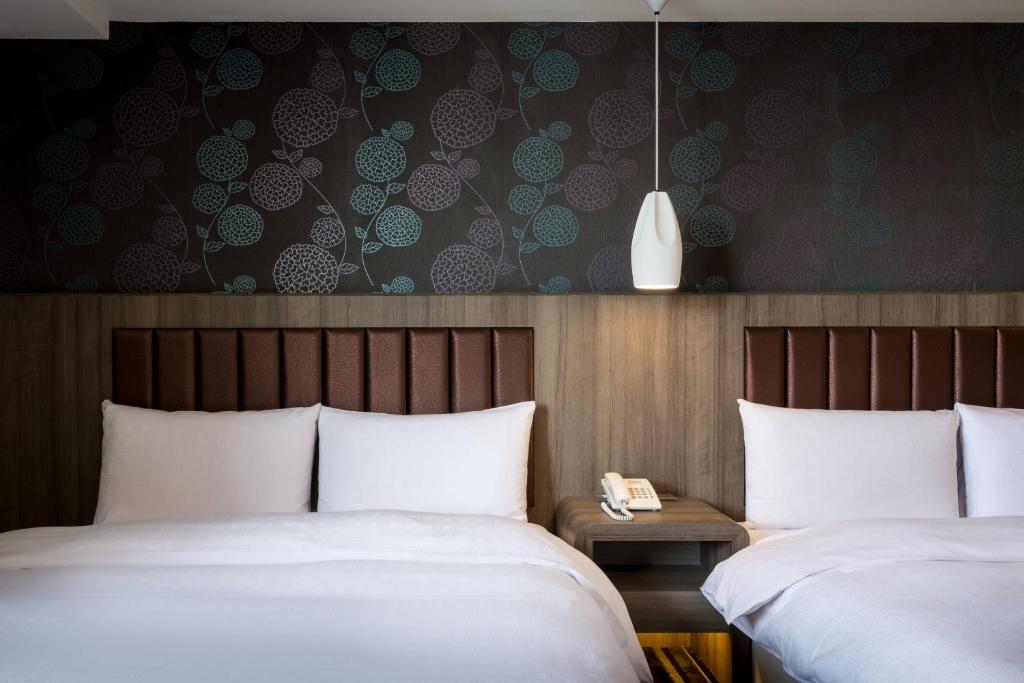 una habitación de hotel con 2 camas y un teléfono en una mesa en JUNG-ZAW BUSSINESS HOTEL, en Taichung