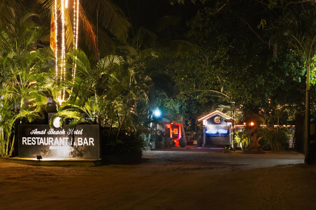 a sign in front of a restaurant at night at Amal Beach Hotel in Bentota