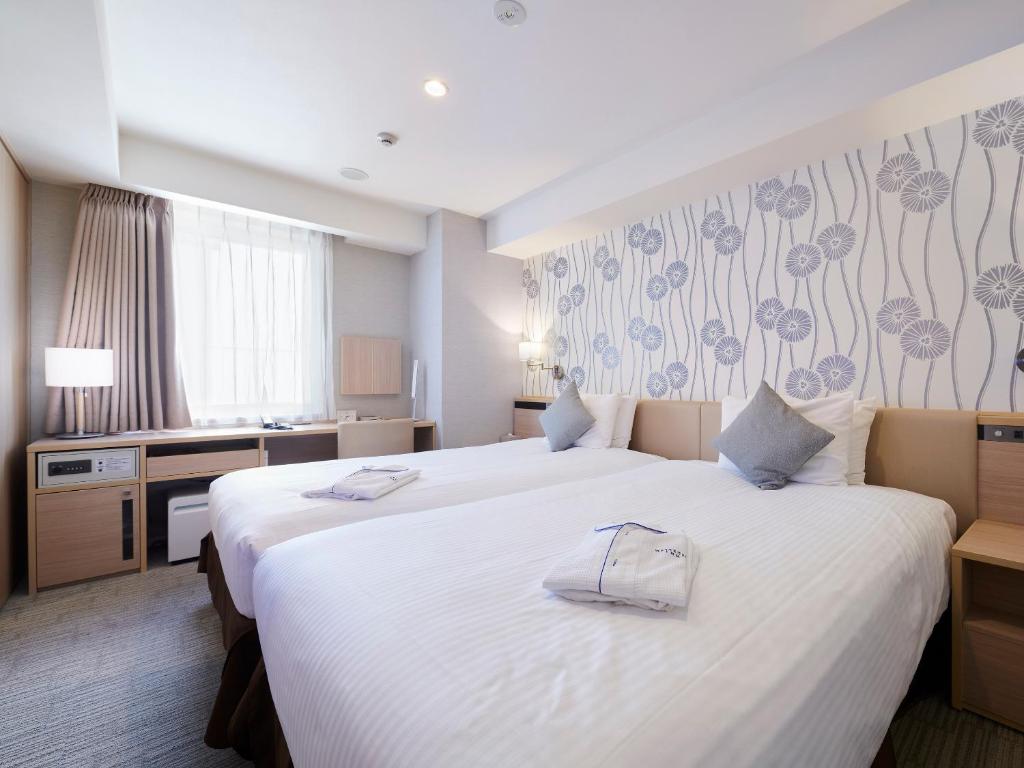 a hotel room with two beds with towels on them at Meitetsu Inn Hamamatsucho in Tokyo