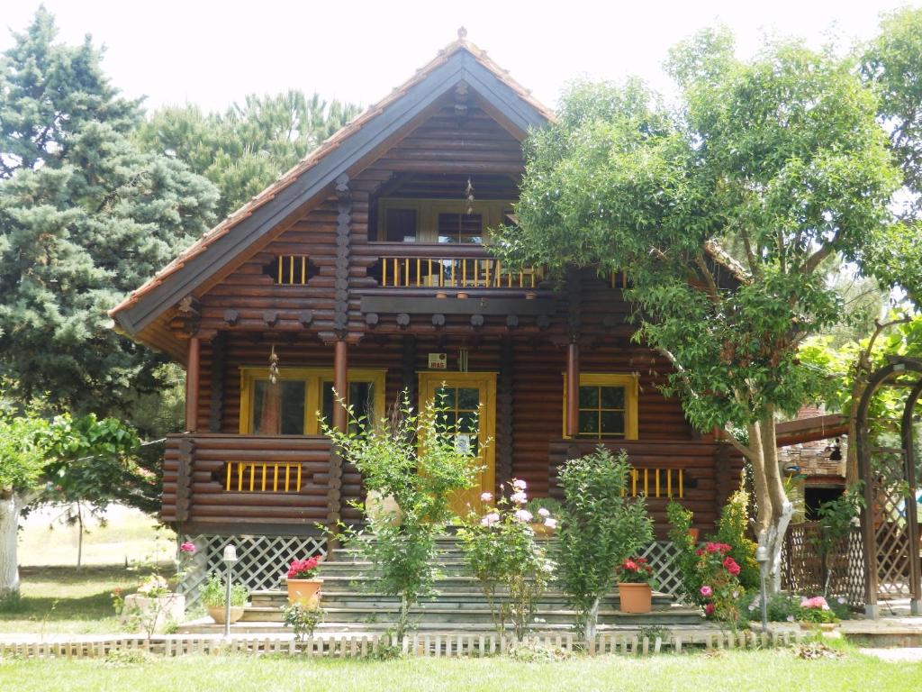 a log cabin with flowers in front of it at Ξύλινο σπίτι (κορμόσπιτο, μεζονέτα, EcoHouse) in Nea Artaki