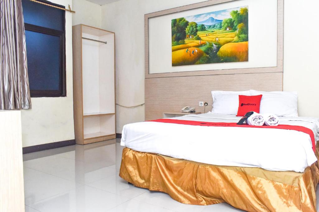 um quarto com uma cama grande e uma almofada vermelha em RedDoorz Plus near Sultan Hasanuddin Airport em Makassar