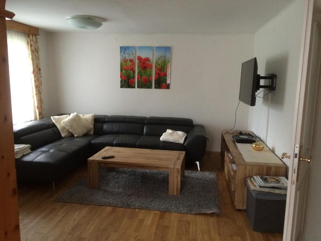 a living room with a black couch and a coffee table at Gemütliches Ferienhaus am Waldrand in Michaelsdorf