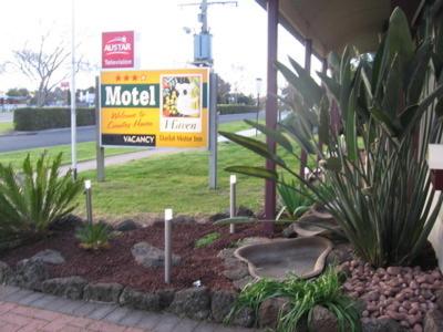 a sign in front of a building with plants at Darlot Motor Inn in Horsham